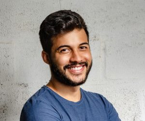 Portrait Photo of Smiling Man with His Arms Crossed Standing In Front of a Wall