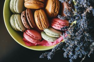 A vibrant assortment of macarons in a bowl, adorned with lavender. Perfect dessert imagery.